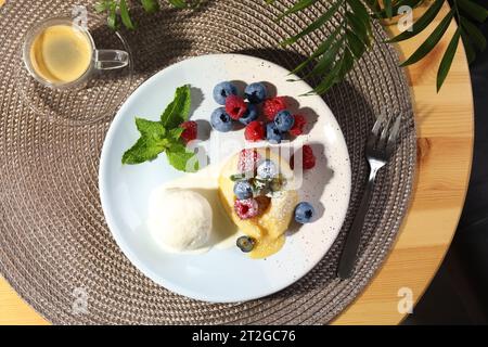 Delizioso fondente alla vaniglia servito con gelato e frutti di bosco sul tavolo, piatto Foto Stock