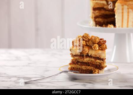 Gocciolatoio al caramello decorato con popcorn e pretzel su un tavolo in marmo bianco, spazio per il testo Foto Stock