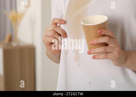 Donna che mostra macchie di caffè sulla camicia al chiuso, primo piano. Spazio per il testo Foto Stock