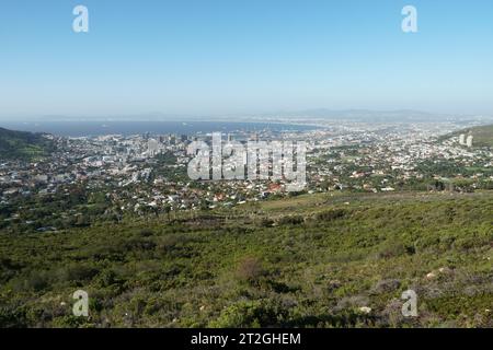 Vista panoramica di città del Capo e dell'oceano Atlantico dai piedi della Table Mountain ricoperta da prati verdi e cespugli. Foto Stock