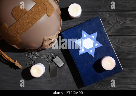 Torah con candele in fiamme, etichette per cani, candele in fiamme e casco militare su sfondo di legno scuro Foto Stock