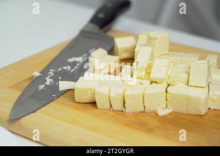 C'è del feta a dadini e un coltello sul tabellone della cucina. Primo piano, sfondo. Foto Stock