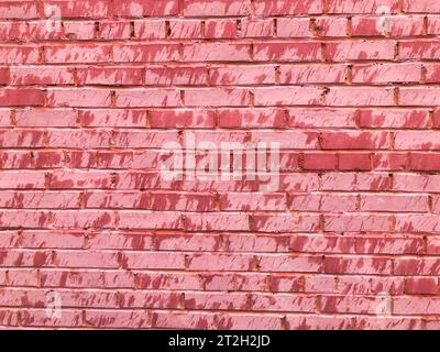 Consistenza di una bella e insolita parete di mattoni rotti di mattoni rettangolari, con cuciture dipinte con vecchio colore rosa shabby. Il retro Foto Stock