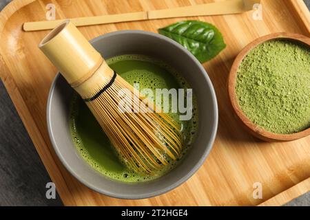 Tazza di tè matcha fresco con frusta di bambù, polvere verde e cucchiaio sul tavolo, vista dall'alto Foto Stock