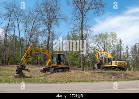 CROW WING CO, Minnesota - 11 MAGGIO 2023: Due escavatori gialli Komatsu vicino a una strada in un cantiere dove verrà costruita una nuova casa. Foto Stock