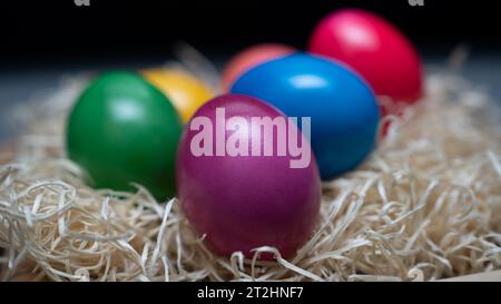 Uova di Pasqua colorate e fatte a mano in paglia con sfondo nero Foto Stock