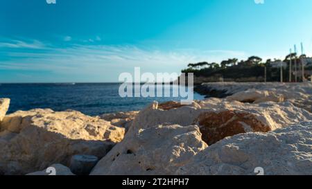 Fuoco selettivo del tramonto su un promontorio con massicce rocce in un porto costiero Foto Stock