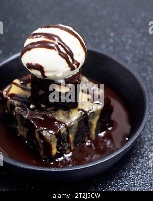 torta brownie al cioccolato e alle noci con gelato alla vaniglia su fondo nero Foto Stock