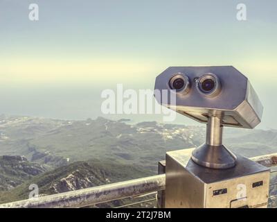 binocolo su una piattaforma di osservazione in metallo grigio. tour panoramico, osservando la vista dalle montagne. binocolo sullo sfondo di un mo Foto Stock