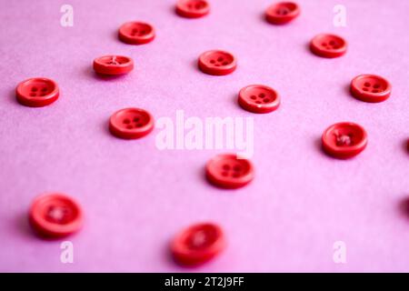 Splendida texture con molti bottoni rotondi rosa per cucire e ricci. Copia spazio. Spianatura piatta. Sfondo rosa e viola. Foto Stock