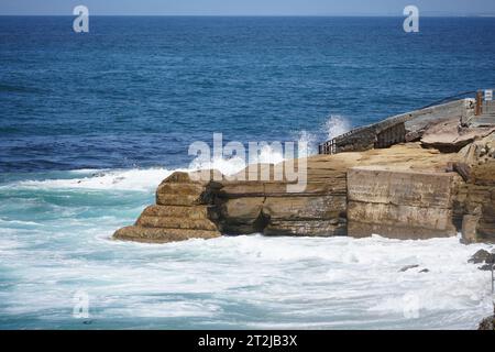 Una pittoresca costa rocciosa con onde ondulate che si infrangono sulla riva Foto Stock