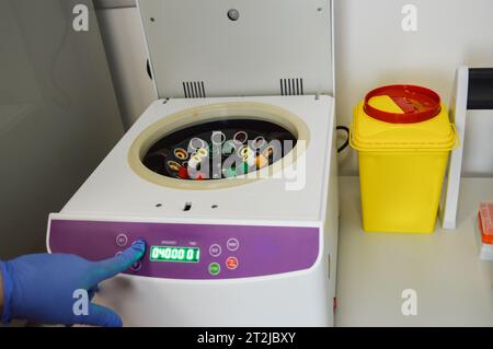 le provette vengono collocate nell'analizzatore per la centrifugazione. esecuzione di test di laboratorio. il medico inserisce la provetta e seleziona la modalità sul dispositivo. ve Foto Stock