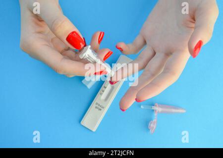 foratura del dito con una lancetta. analisi rapida del sangue. strisce reattive per la diagnosi del coronavirus. una ragazza con una manicure rossa fa un'analisi e.. Foto Stock