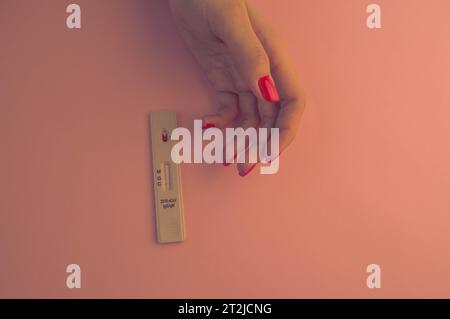 ragazza con una manicure rossa brillante che fa un test per il coronavirus. un esame del sangue per determinare l'infezione a casa. test rapido rapido, diagnostica dello stato. Foto Stock