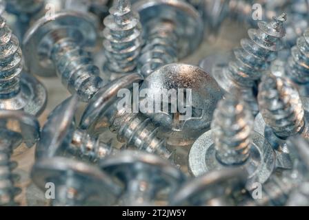 Pila casuale di viti zincate, sfondo industriale astratto Foto Stock