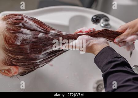il parrucchiere professionale lava i capelli con lo shampoo al cliente in un salone di bellezza Foto Stock