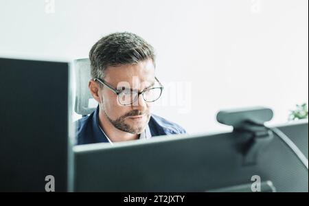 Lavoro remoto e concattività modrn. Incontro virtuale con molti partecipanti online. Webinar. Uomo d'affari che parla online con i dipendenti tramite connessione video Foto Stock