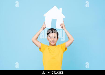 Simpatico ragazzo delle gare miste in maglietta gialla che solleva le braccia con la cartiera e sorride mentre pubblicizza l'agenzia immobiliare su sfondo blu Foto Stock