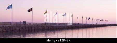 Bandiere al tramonto lungo frangiflutti a Santa Barbara porto, California Foto Stock