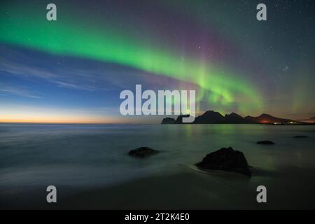 Aurora boreale - l'aurora boreale splende nel cielo sul mare e sulle montagne, Storsandnes, FlakstadÃ¸y, Isole Lofoten, Norvegia Foto Stock