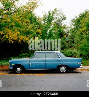 Una vecchia auto si trova sotto un albero di colore autunnale a Kansas City, Missouri. Foto Stock