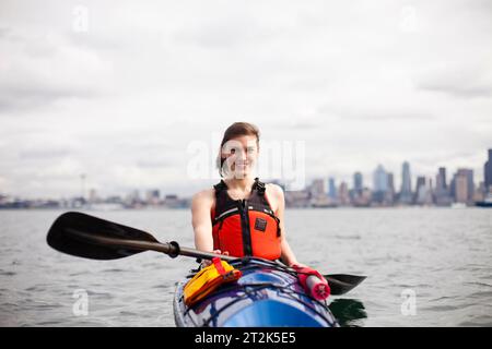 Una giovane ragazza canoa in una giornata nuvolosa nel Puget Sound al largo della costa del centro di Seattle. Foto Stock