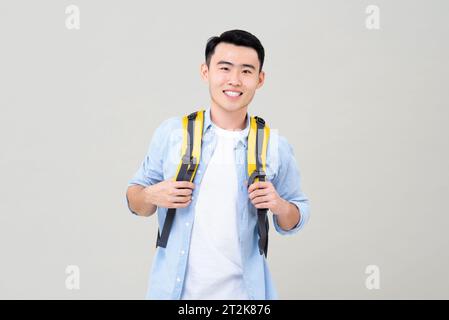 Porttrait di un giovane turista asiatico sorridente con uno studio di zainetto isolato su sfondo grigio Foto Stock