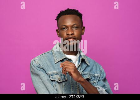 Ritratto di un giovane e affascinante modello africano in posa su uno sfondo isolato in studio di colore viola Foto Stock