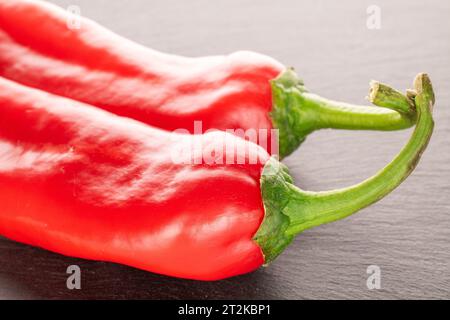 Due peperoni rossi dolci su pietra di ardesia Foto Stock