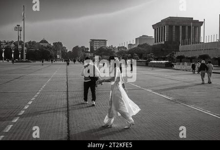 Una donna vietnamita in un tradizionale ao dai rosa e bianco cammina in Piazza Ba Dinh accanto al Mausoleo di ho chi Minh nel centro di Hanoi, in Vietnam. Foto Stock