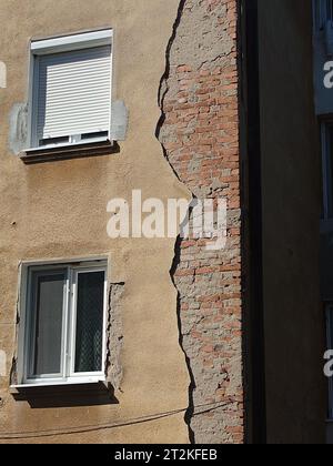 Facciata dell'edificio fatiscente. Intonaco esterno incrinato e sbucciato su pareti in mattoni e vecchie telai delle finestre, niente persone Foto Stock