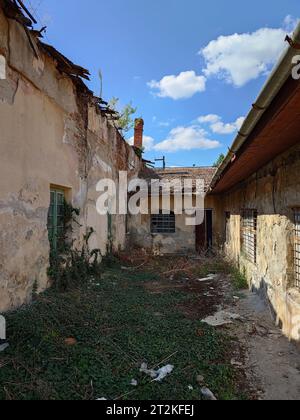 Facciata dell'edificio fatiscente. Intonaco esterno incrinato e sbucciato su pareti in mattoni e vecchie telai delle finestre, niente persone Foto Stock