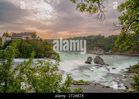 Vista al tramonto sulle rive meridionali delle Cascate del Reno e sul castello Laufen in cima alla collina. Cascate del Reno, le cascate più grandi d'Europa nella Svizzera orientale. Foto Stock