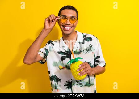 Foto di un bravo ragazzo che indossa un abito elegante che si diverte godendosi il weekend estivo gustosi cocktail isolati su sfondo giallo Foto Stock