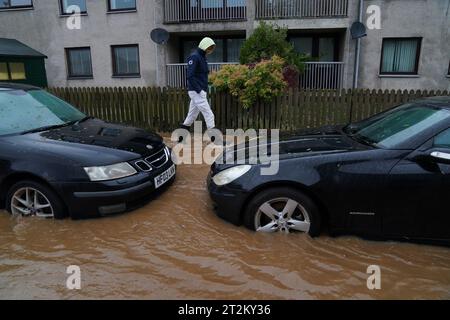 Una persona cammina attraverso le acque alluvionali a Brechin, in Scozia, mentre Storm Babet colpisce il paese. In Scozia, così come in alcune parti del nord dell'Inghilterra e delle Midlands, sono in atto avvertimenti sulle inondazioni. Migliaia di persone sono rimaste senza energia elettrica e sono state esposte a inondazioni dovute a piogge "senza precedenti" nella Scozia orientale, mentre Babet è destinata a diffondersi nell'Inghilterra settentrionale e orientale venerdì. Data immagine: Venerdì 20 ottobre 2023. Foto Stock