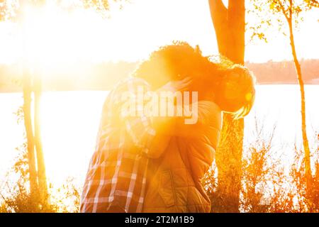 Un momento tenero come una bella coppia interrazziale, un uomo arabo e una donna caucasica, condividono un abbraccio romantico, che sta per baciarsi appassionatamente alla luce calda di un tramonto durante la loro avventura di viaggio. Coppia interrazziale che condivide Sunset Kiss. Foto di alta qualità Foto Stock