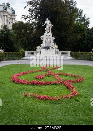 Clef fatto di fiori, dietro di esso monumento in onore del compositore Wolfgang Amadeus Mozart, Burggarten, Vienna, Austria Foto Stock