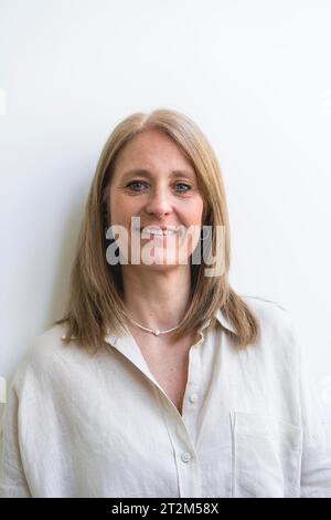 Bella donna di mezza età che guarda la fotocamera appoggiata a una parete bianca Foto Stock