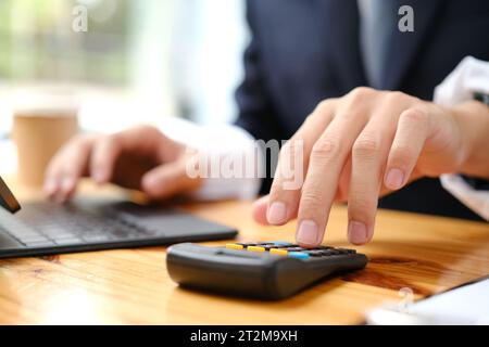 Le mani di un uomo d'affari che lavora con calcolatrici e laptop.. Foto Stock