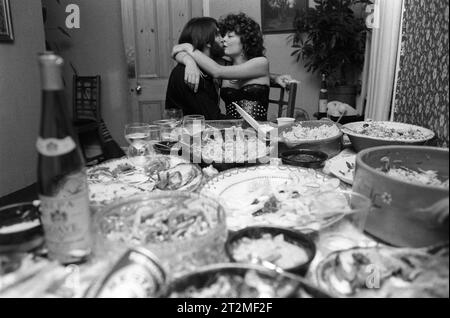Festa di Natale di classe media un paio di baciarsi in cucina - sala da pranzo, dove il cibo è stato preparato e mangiato a metà. Wimbledon, Londra, Inghilterra dicembre 1983. 1980S UK HOMER SYKES Foto Stock