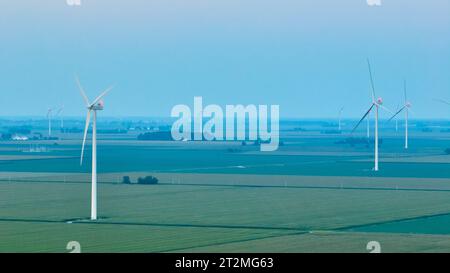 Luci aeree rosse sulle turbine eoliche al crepuscolo nelle nebbiose serate sui terreni agricoli Foto Stock