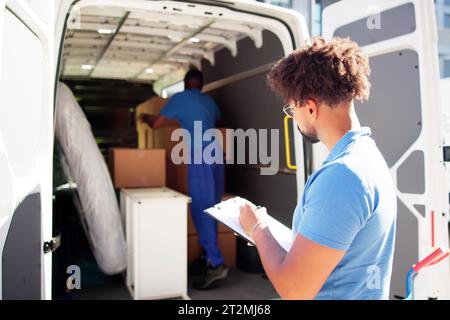 I traslocatori che controllano le caselle di consegna e compilano il documento Foto Stock