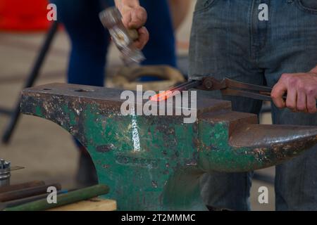 Farrier che batte ferro caldo rosso o acciaio e crea un ferro di cavallo. il santo patrono dei fabbri è Sant'Eligio. Foto Stock