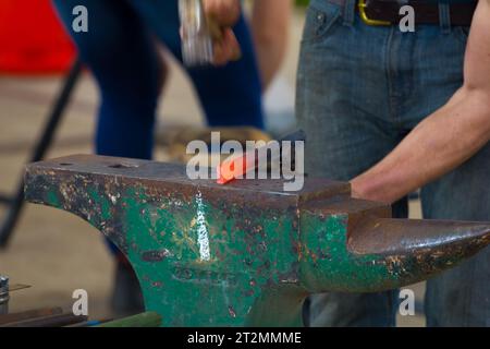 Farrier batte un ferro o un ferro di cavallo d'acciaio. il santo patrono dei fabbri è Sant'Eligio. Foto Stock