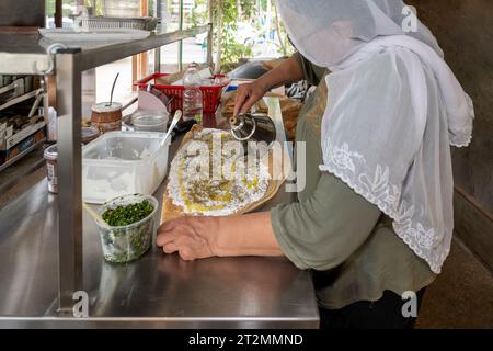Hurfeish, Israele - 14 agosto 2023: Una donna drusa prepara la pita drusa con Labneh e Tabbouleh in un ristorante a Hurfeish, nel nord di Israele. Foto Stock