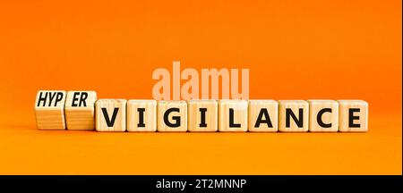 Simbolo di vigilanza o ipervigilanza. Parole concettuali Vigilance Hypervigilance su blocchi di legno. Bellissimo sfondo arancione. Psicologia vigi Foto Stock