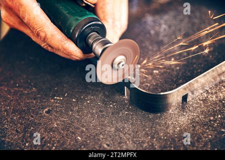 Il lavoratore taglia il metallo con scintille di taglio del metallo che volano durante la lavorazione dell'acciaio Foto Stock