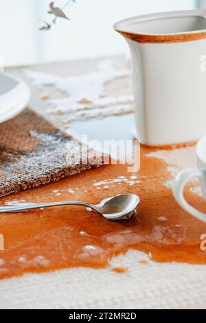 dettaglio di un tavolo coperto da una tovaglia beige con una pozza di caffè che è stata accidentalmente versata su di esso Foto Stock