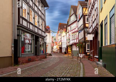 Antica strada medievale tradizionale con case in legno metà illuminate di sera al tramonto. Marburg. Germania. Foto Stock