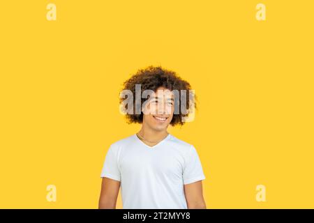 Ritratto di una bella e sorridente razza mista Afro-italiana generazione z adolescente con spessi capelli ricci su sfondo giallo. Felici giovani multietnici Foto Stock